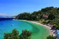 Türkisblaues Wasser, Sandstrand und bewaldete Küste einer Bucht.