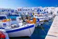 Traditionelle griechische Fischerboote im Hafen, festgemacht am Kai, vor dem Hintergrund der typischen weißen Architektur.