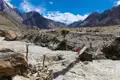 Wanderer überquert eine Hängebrücke über einen reißenden Fluss im Hochgebirge.