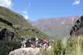 Wanderer ruhen sich auf einem Felsen aus und betrachten die Bergkette im Hintergrund.