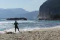 Person am Strand mit Blick auf das Meer und die Klippen.