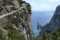 Wanderer auf einem schmalen Küstenpfad mit Blick auf das Meer und Felsformationen.