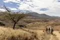 Wandergruppe auf einem Pfad in einer trockenen, vulkanischen Landschaft.