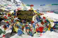 Gebetsfahnen und Schild am Thorong-La Pass (5416 m), der die Grenze zwischen Manang und Mustang markiert und einen Höhepunkt des Annapurna Circuit Treks darstellt.