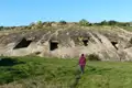 Felsengräber mit rechteckigen Eingängen in einer Hügellandschaft.