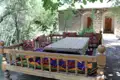 Traditioneller Essbereich im Freien mit Holztisch, -bänken und bunten Textilien.