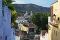 Blick über die Dächer der Stadt auf eine Kirche mit zwei Türmen vor dem Hintergrund der umliegenden Landschaft.