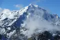Schneebedeckter Berggipfel mit Wolken.