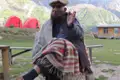Ein lokaler Mann in traditioneller Kleidung sitzt vor dem Campingplatz in den Bergen.