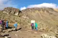 Wanderer machen eine Pause an einem Schild auf einem Bergwanderweg.