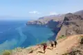 Wanderer auf einem Küstenpfad mit Blick auf das Meer und die felsige Küste.