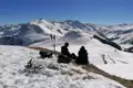 Schneeschuhe und Wanderstöcke liegen im Schnee, während Wanderer eine Pause in den Bergen einlegen und die Aussicht genießen.