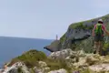 Wanderer auf einem Küstenpfad mit Blick auf einen Leuchtturm.