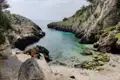 Klares, türkisfarbenes Wasser in einer felsigen Bucht.
