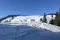 Verschneiter Hang mit Hochsitz und Bäumen im Winter.
