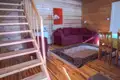 Innenansicht des Wohnbereichs mit Holztreppe, Sofa und Essbereich.