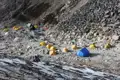 Basislager mit Zelten in einer steinigen Gebirgslandschaft.
