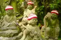 Gruppe von Steinstatuen mit roten und weißen Mützen, möglicherweise religiöse Figuren.