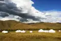 Traditionelle Jurtenunterkünfte inmitten einer hügeligen Landschaft.