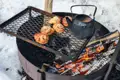 Zubereitung von Zimtschnecken und einem Heißgetränk über einem offenen Feuer im Schnee.