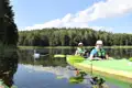 Zwei Kajakfahrer auf einem See mit einem Schwan im Vordergrund.