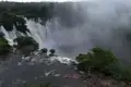 Ein beeindruckender Wasserfall mit starkem Wasserfluss, umgeben von üppiger Vegetation und in Nebel gehüllt.