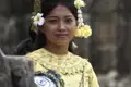 Eine Frau in traditioneller Kleidung, die goldene Verzierungen und Blumen im Haar trägt.