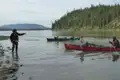 Kanufahren auf einem Fluss mit einem Führer, der vom Ufer aus Anweisungen gibt.