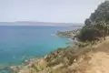 Felsige Küste mit türkisfarbenem Meer und Blick auf die Berge im Hintergrund.