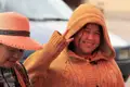 Person im senffarbenen Kapuzenpullover macht das Friedenszeichen.