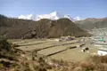 Terrassierte Felder und Gebäude vor der Kulisse schneebedeckter Berge.