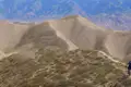 Sandige Hügel und ein schmaler Pfad in einer Berglandschaft.
