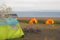 Campingplatz am Ufer mit zwei Zelten und Fahrrädern, bereit für eine Radtour.