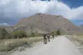 Drei Mountainbiker auf einer Schotterstraße in bergigem Gelände.
