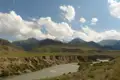 Blick auf einen Fluss, der durch ein Tal fließt, umgeben von Bergen.