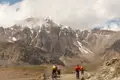 Mountainbiker auf einer Bergstrecke mit schneebedecktem Gipfel im Hintergrund.