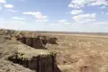 Reisender am Rand einer Klippe mit Blick auf eine weitläufige Wüstenlandschaft.