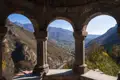 Panoramablick durch die Bögen eines historischen Gebäudes auf die umliegende Berglandschaft und das Tal.