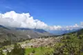 Blick auf ein Andendorf mit umliegenden Bergen und Wolken.