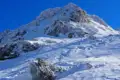 Verschneiter Berghang mit sichtbaren Spuren im Schnee, möglicherweise von Skifahrern oder Snowboardern.