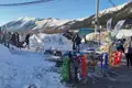 Schlitten, Schneesportgeräte und Menschen in einer verschneiten Berglandschaft.