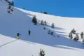 Zwei Skitourengeher steigen einen verschneiten Hang hinauf.