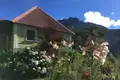 Grünes Haus mit Garten und Berglandschaft im Hintergrund