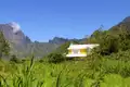 Gelbes Haus mit weißer Dach in einer bergigen Landschaft.