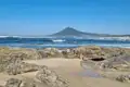 Felsiger Küstenabschnitt mit Blick auf einen Berg am Meer.