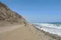 Blick über die Dächer einer Küstenstadt auf die Bucht und die bewaldeten Hügel.