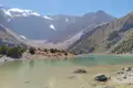 Panoramablick auf einen Bergsee mit schneebedeckten Gipfeln im Hintergrund.