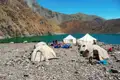 Zelte und Maultiere am Ufer eines Bergsees.