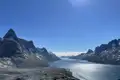 Panoramablick auf einen Fjord in Grönland mit Bergen und blauem Himmel.