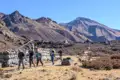 Wanderer auf einem Bergpfad mit Gebetsfahnen und Stupas im Hintergrund.